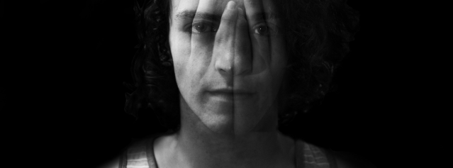 Black and white portrait of young man with a reflection of hands on his face