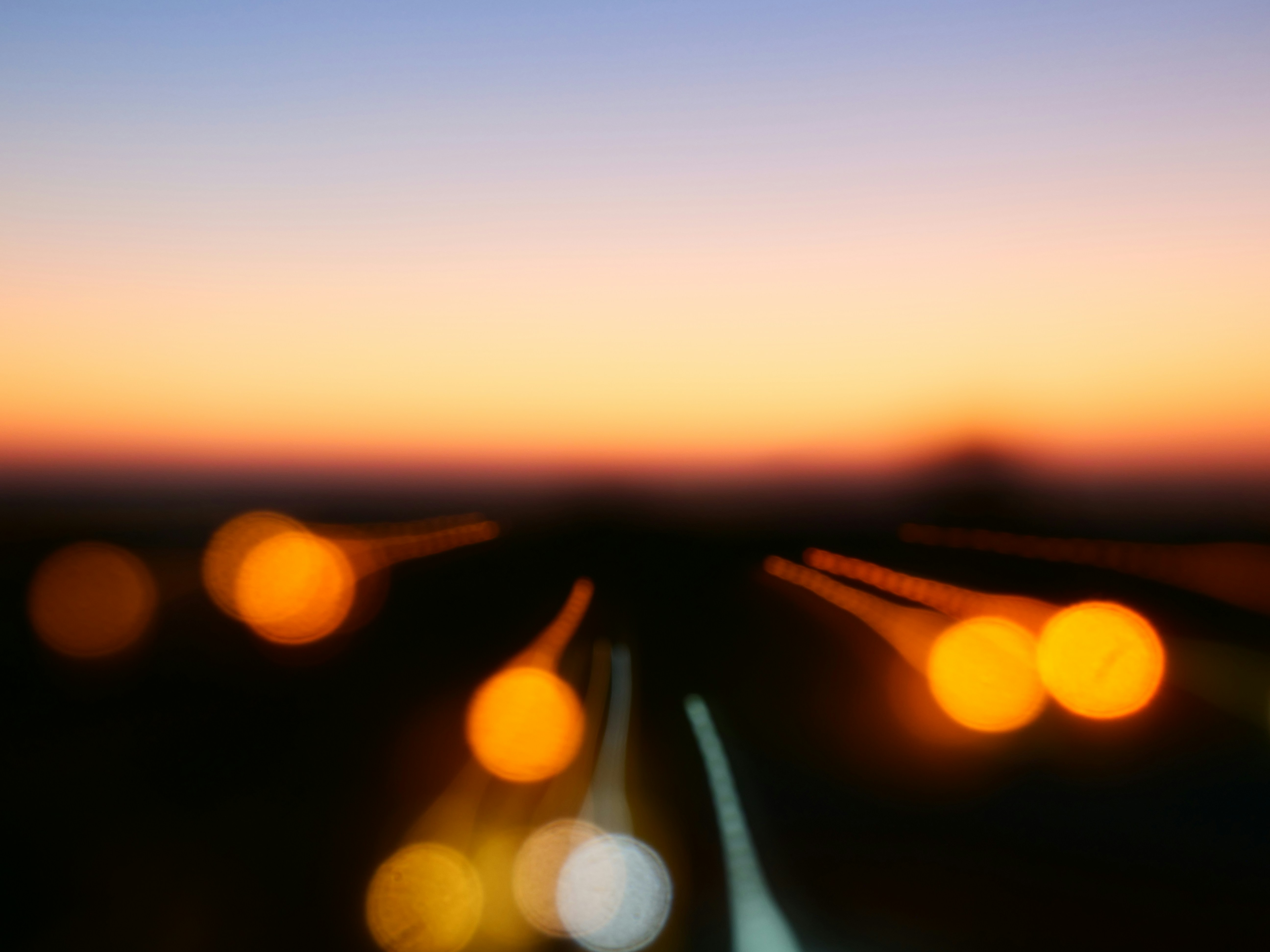 Immagine di strada, all'orizzone un tramonto, il tutto estremamente sfuocata.