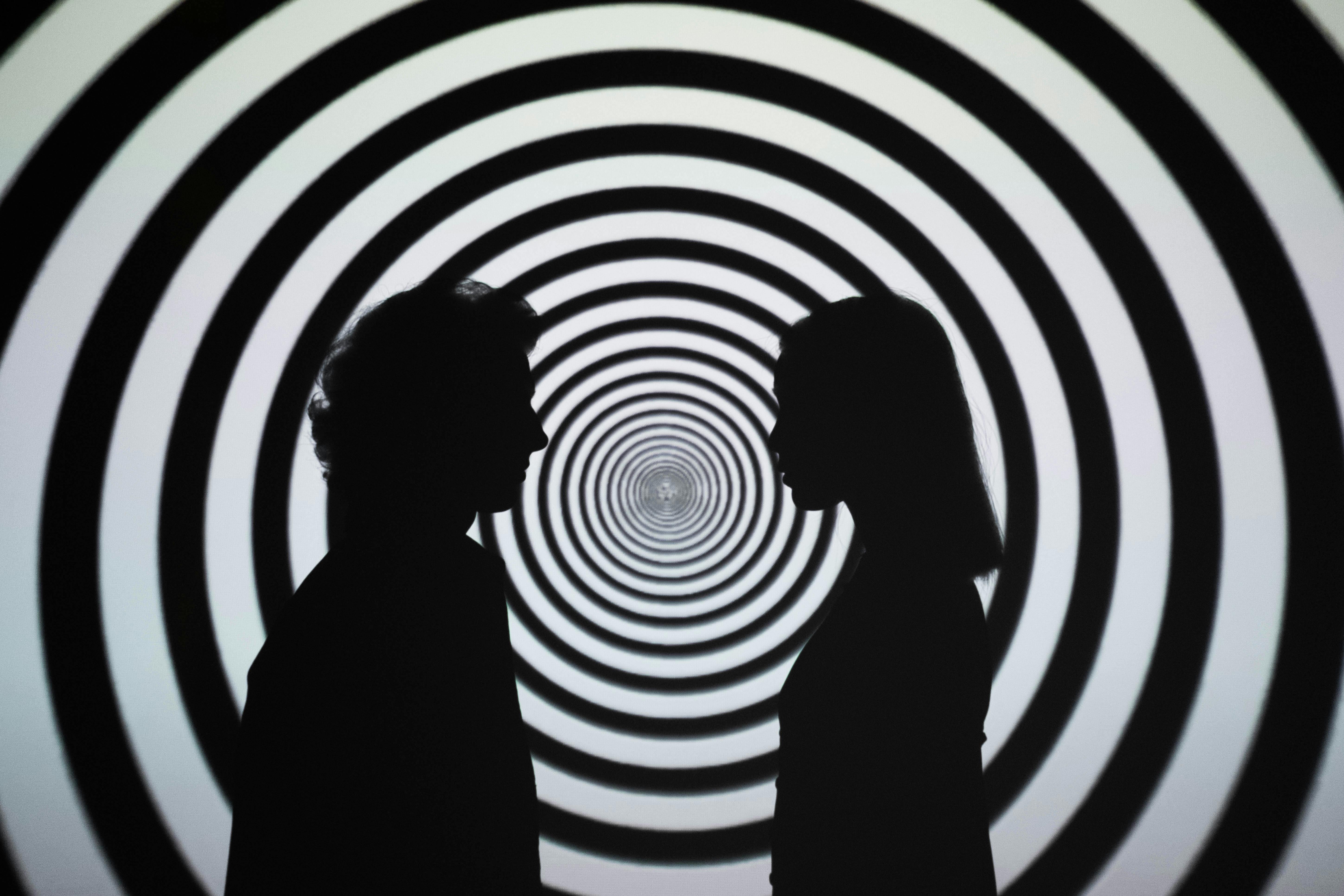 Spirale a vortice bianco e nero, davanti due figure in contro luce l'una di fronte all'altra