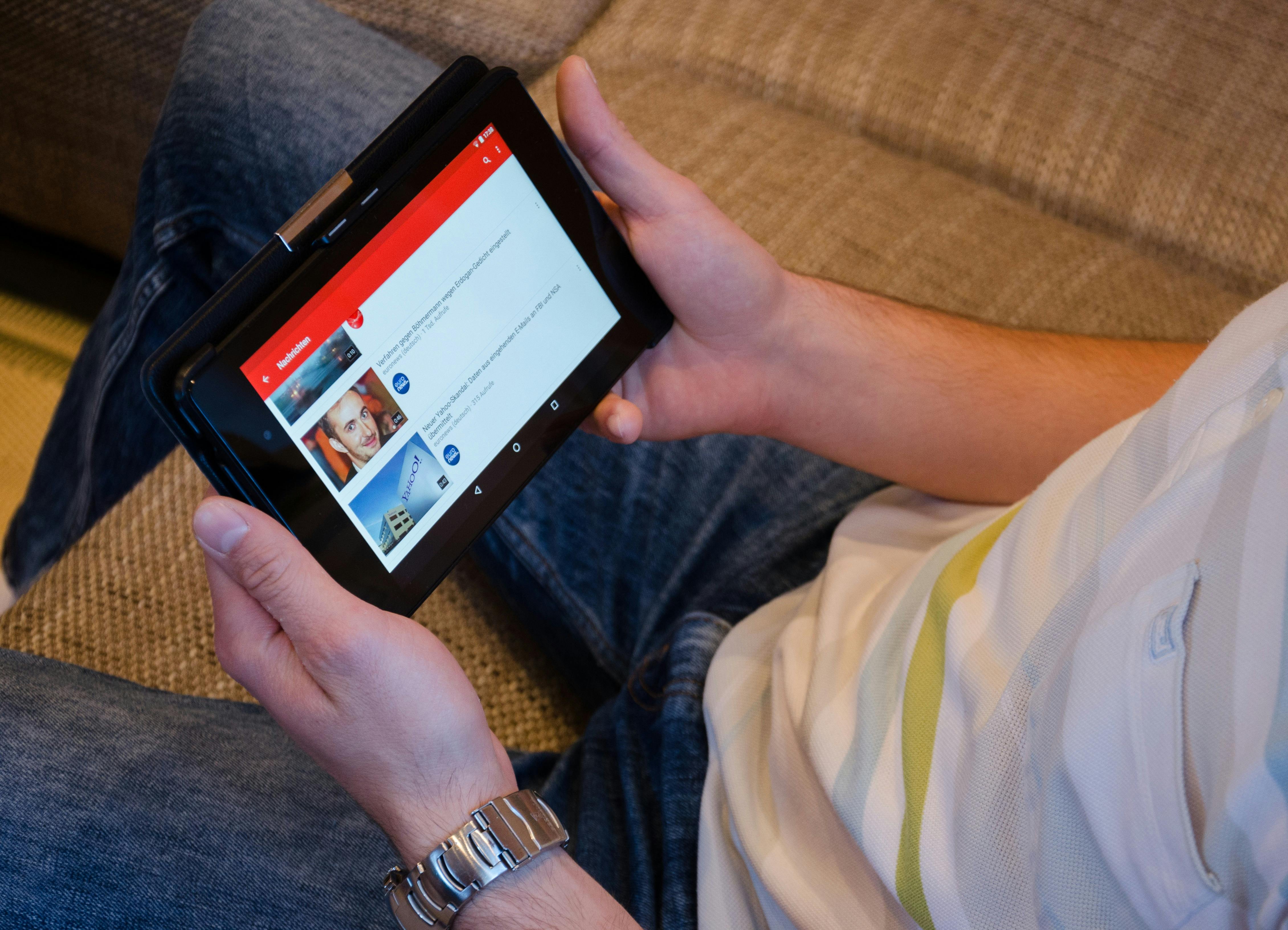 Persona che tiene un iPad in mano aperto su YouTube.